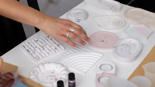 Hand arranging decorative items on white table.