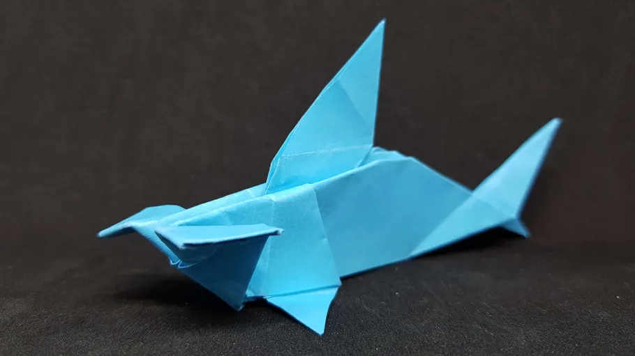 Blue origami shark on black background.