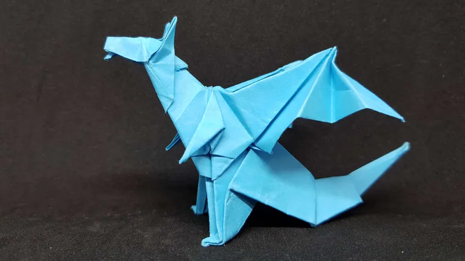 Blue origami dragon on black background.