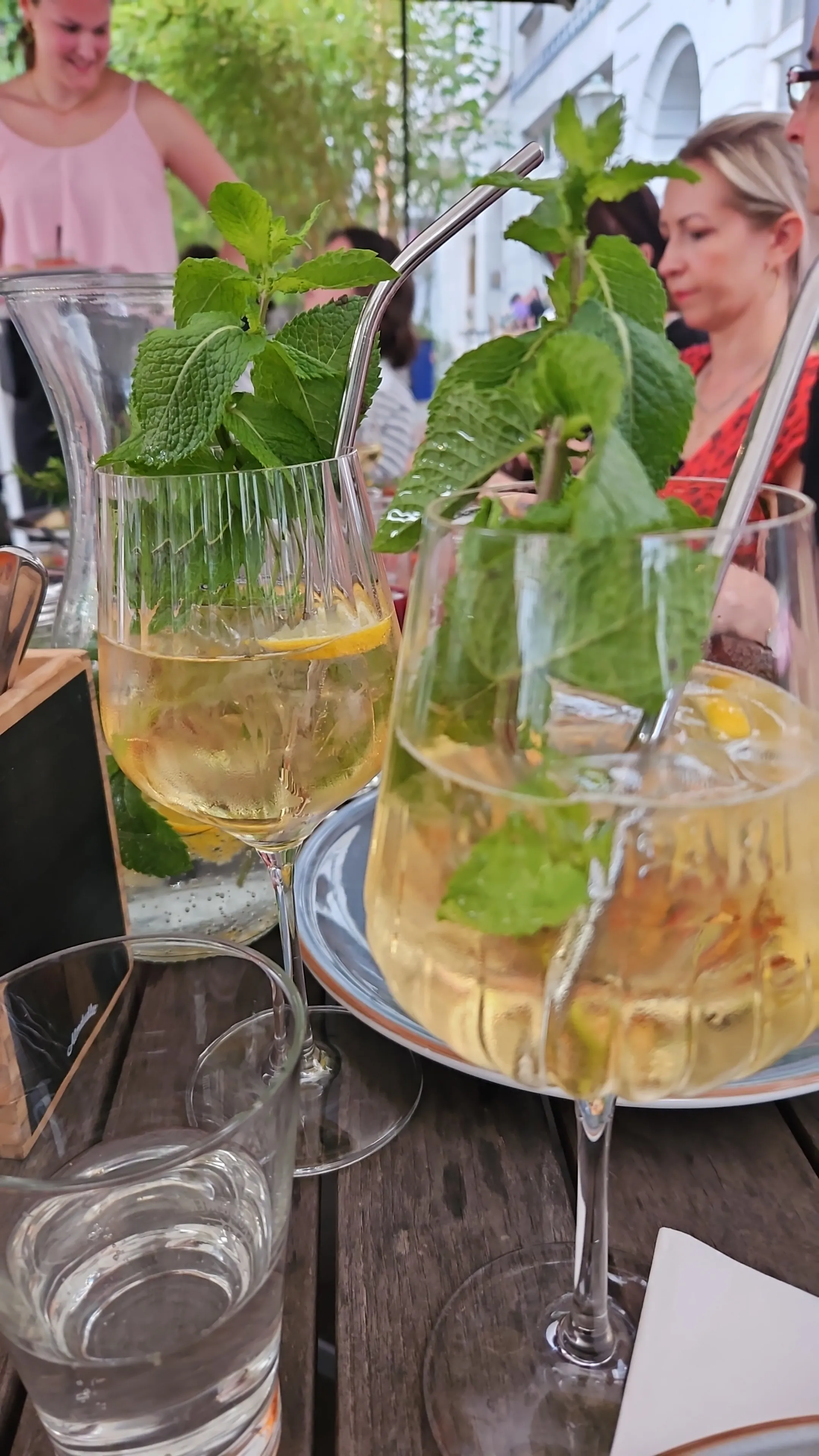 Gläser mit Cocktails und Minze auf Holztisch.