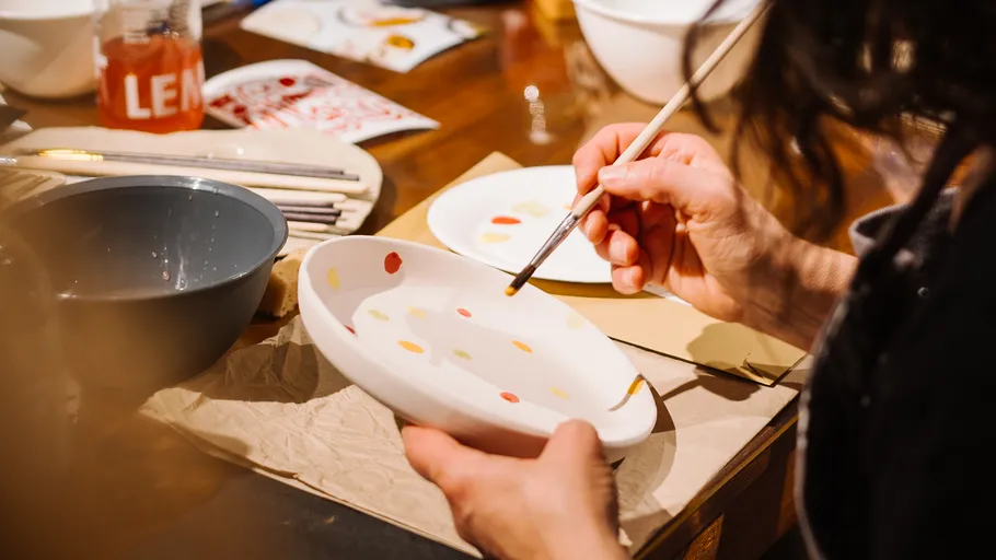 Person painting a ceramic dish indoors.