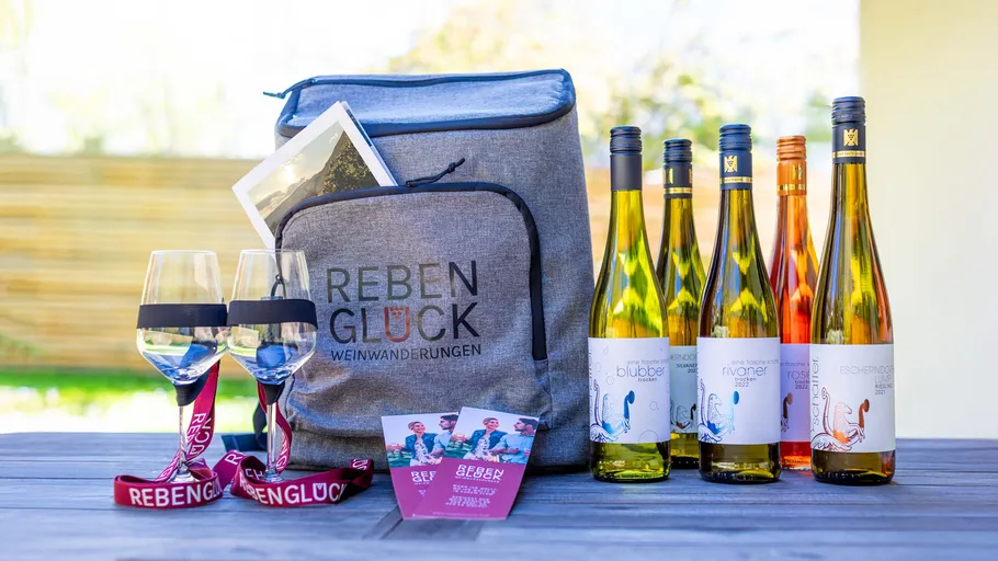 Wine bottles, glasses, and bag on table.