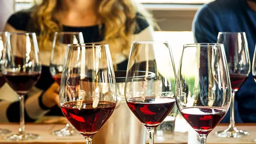 Wine glasses on table with people around.