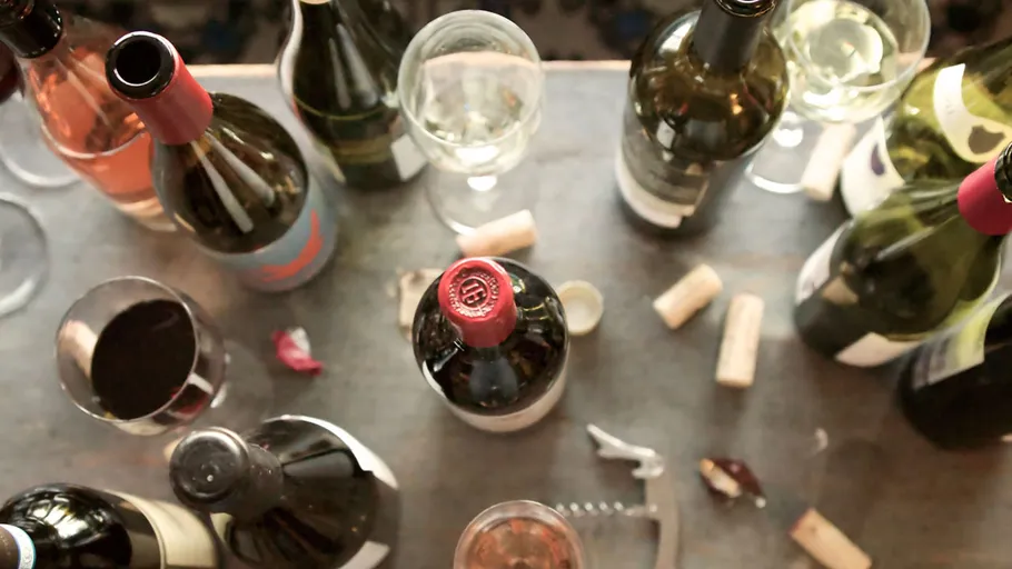 Wine bottles and glasses on table viewed from above.