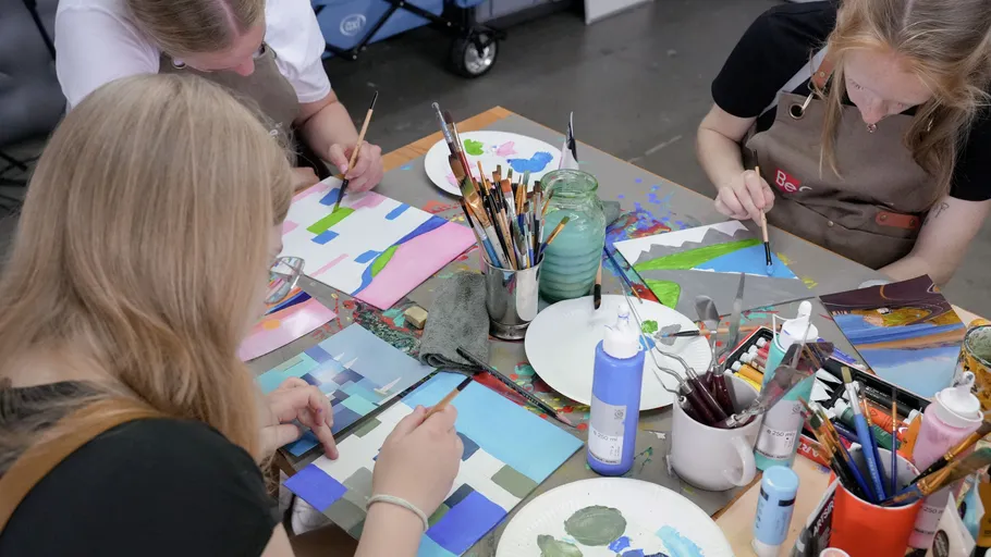 Menschen malen abstrakte Kunst an einem Tisch.