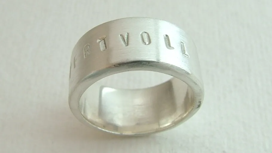 Silver ring with engraved word 'WERTVOLL'.