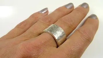 Hand trägt strukturierten Silberring.