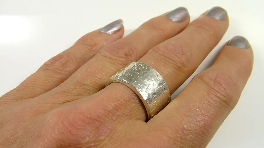 Hand trägt strukturierten Silberring.
