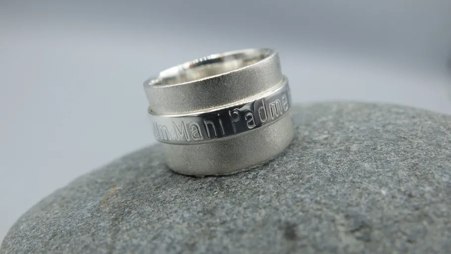 Silver ring with inscription on stone surface.
