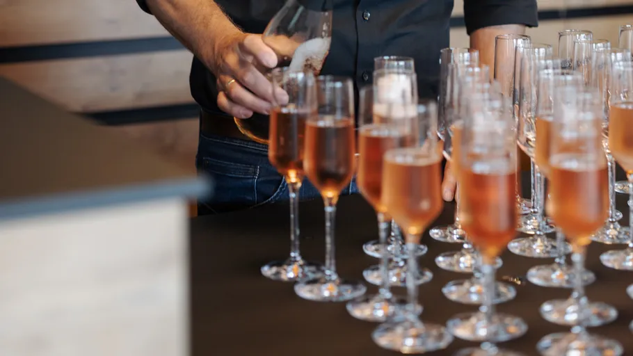Person gießt Champagner in mehrere Gläser ein.