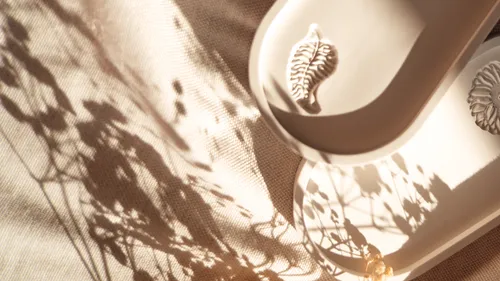 Ceramic tray with shadows on fabric surface.