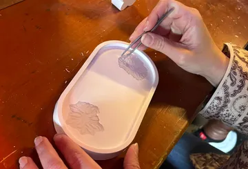 Hände machen ein Blätterdesign in einer Form.