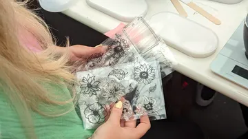 Person holds transparent floral stamps indoors.