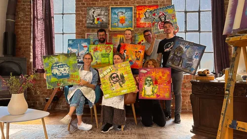 Group holding colorful paintings in art studio.