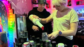 Two people preparing drinks at a bar.