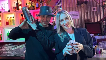 Two people posing in a bar setting.