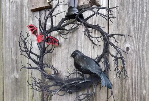 Kranz mit Krähe und Fledermaus an Holztür.