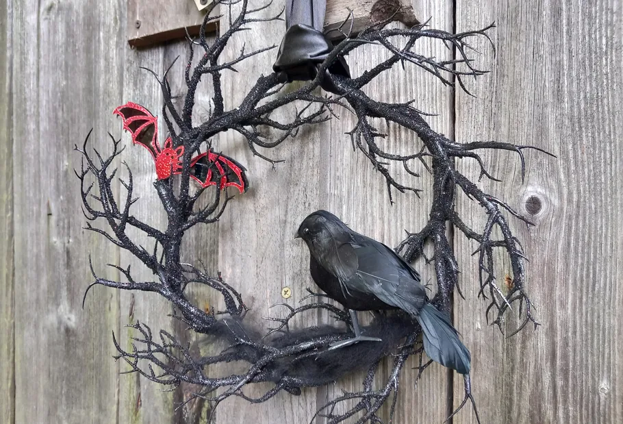 Kranz mit Krähe und Fledermaus an Holztür.