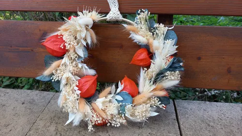 Blumenkranz mit roten und beigen Blumen draußen.