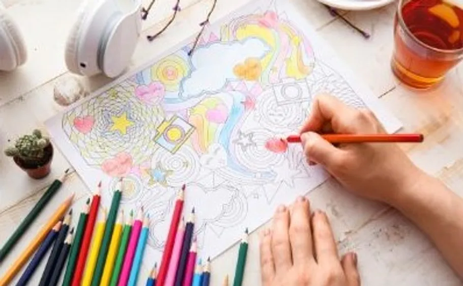 Hand coloring pattern with pencils on table.