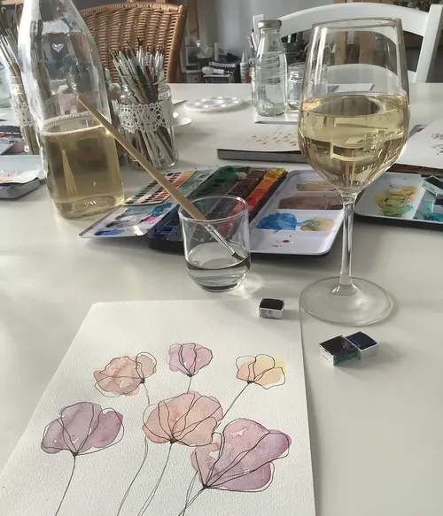 Watercolor painting setup with flowers and wine.