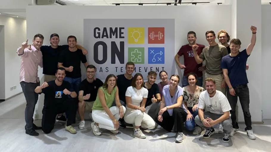 Group posing in front of team event sign.