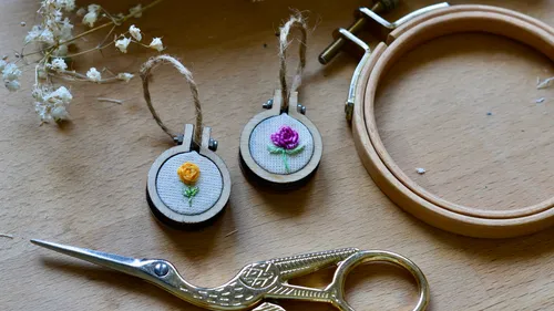 Small embroidery frames with flower designs on table.