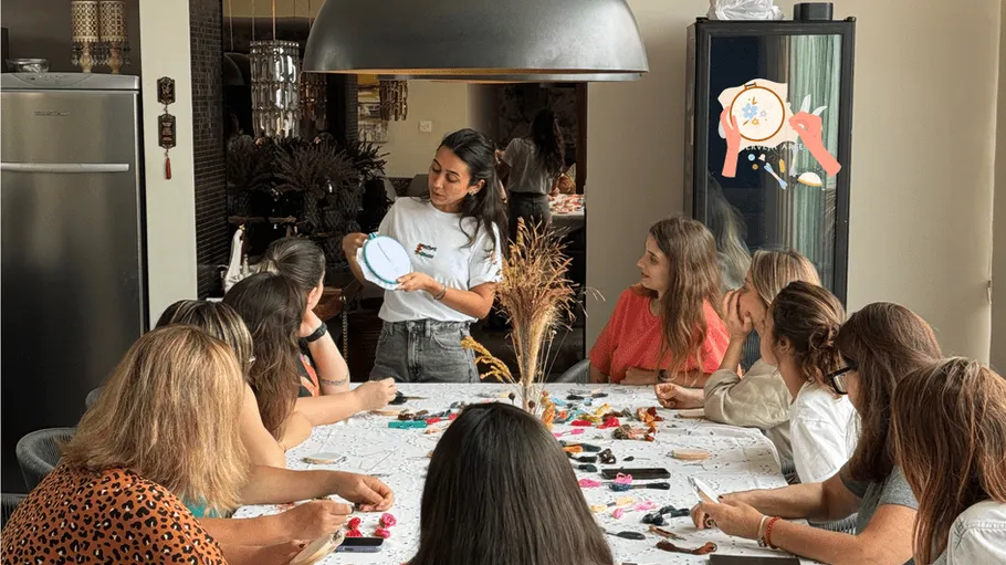 Woman teaching embroidery at table workshop.