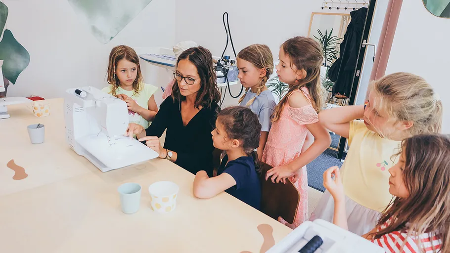 Frau unterrichtet Kinder im Nähen im Klassenzimmer.