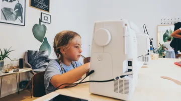 Kind näht mit Maschine im Kreativraum.
