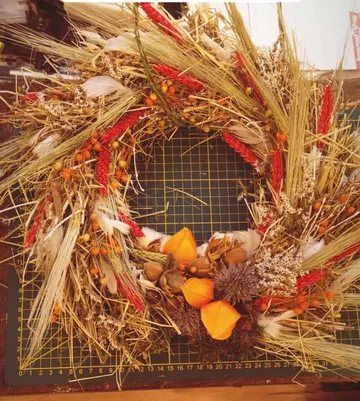Decorative wreath with dried flowers on mat.