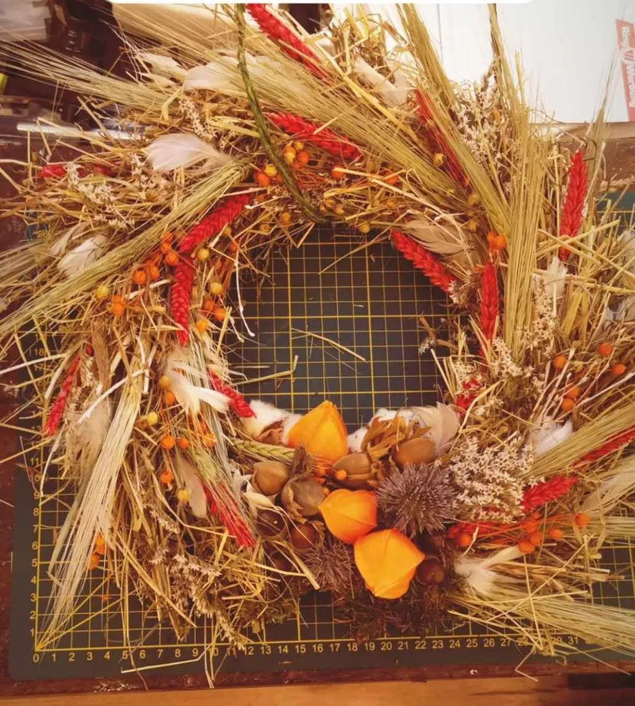 Decorative wreath with dried flowers on mat.