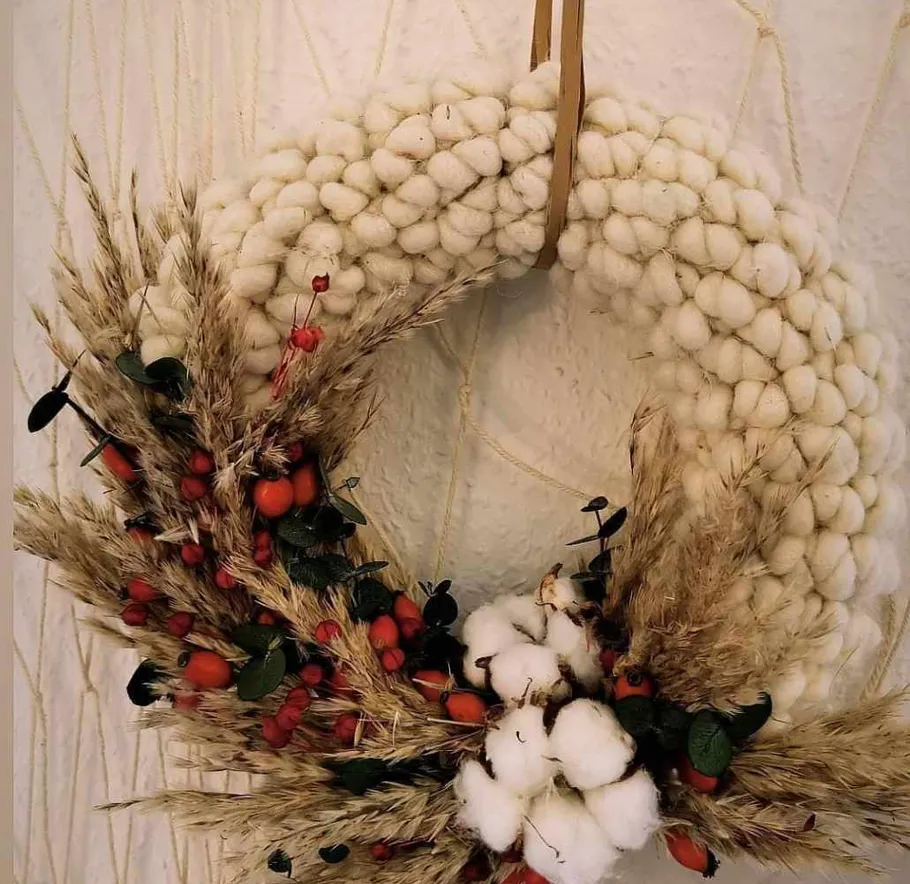 Woven wreath with berries and wheat on wall.