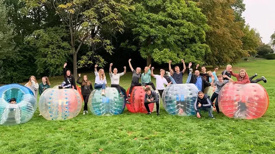 Group in bubble suits outdoors, smiling and cheering.