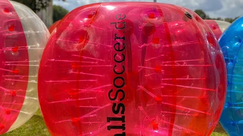 Bunte aufblasbare Zorb-Bälle auf Rasenfläche.