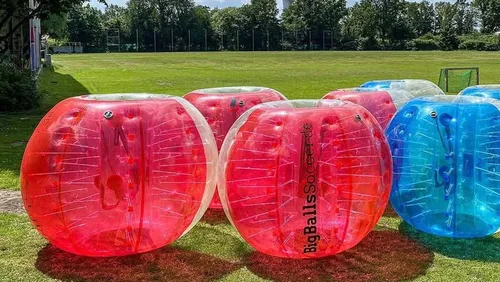 Inflatable balls on a grassy field outdoors.