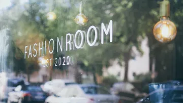 Shop window with 'Fashion Room' text, street view.