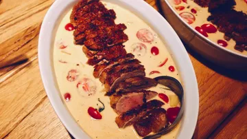 Sliced meat in creamy sauce with tomatoes.