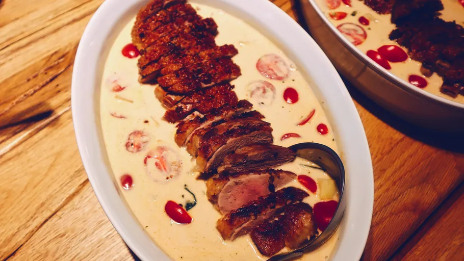 Geschnittenes Fleisch in Sahnesoße mit Tomaten.