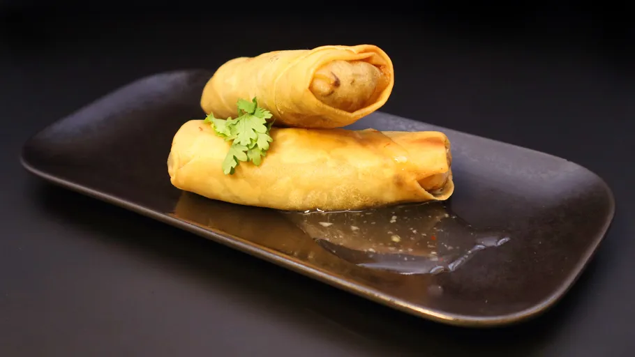 Two spring rolls garnished with parsley on plate.