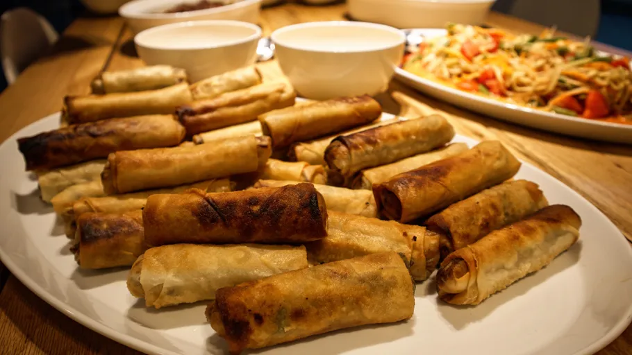 Spring rolls on a plate, with bowls nearby.