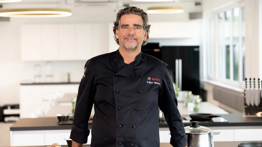 Chef in black coat in modern kitchen.