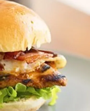 Burger with bacon and lettuce on plate.