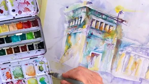 Hand malt Gebäude mit Aquarellkasten daneben.
