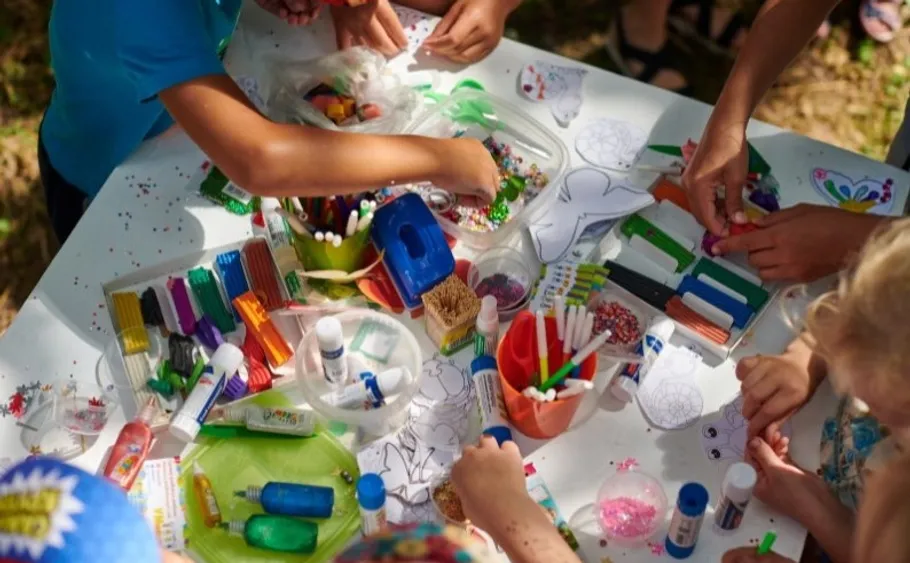 Children crafting with colorful materials at a table.
