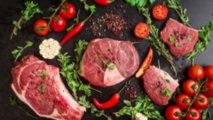 Rohes Fleisch und Gemüse auf schwarzer Fläche.
