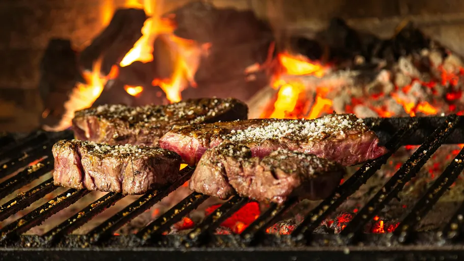 Steaks grillen über offenen Flammen im Freien.