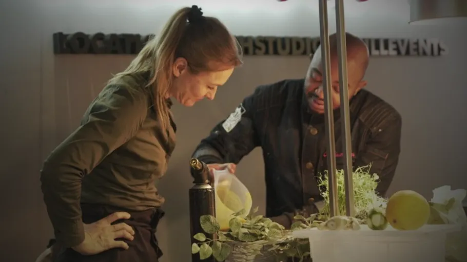 Two chefs discussing ingredients in a kitchen.