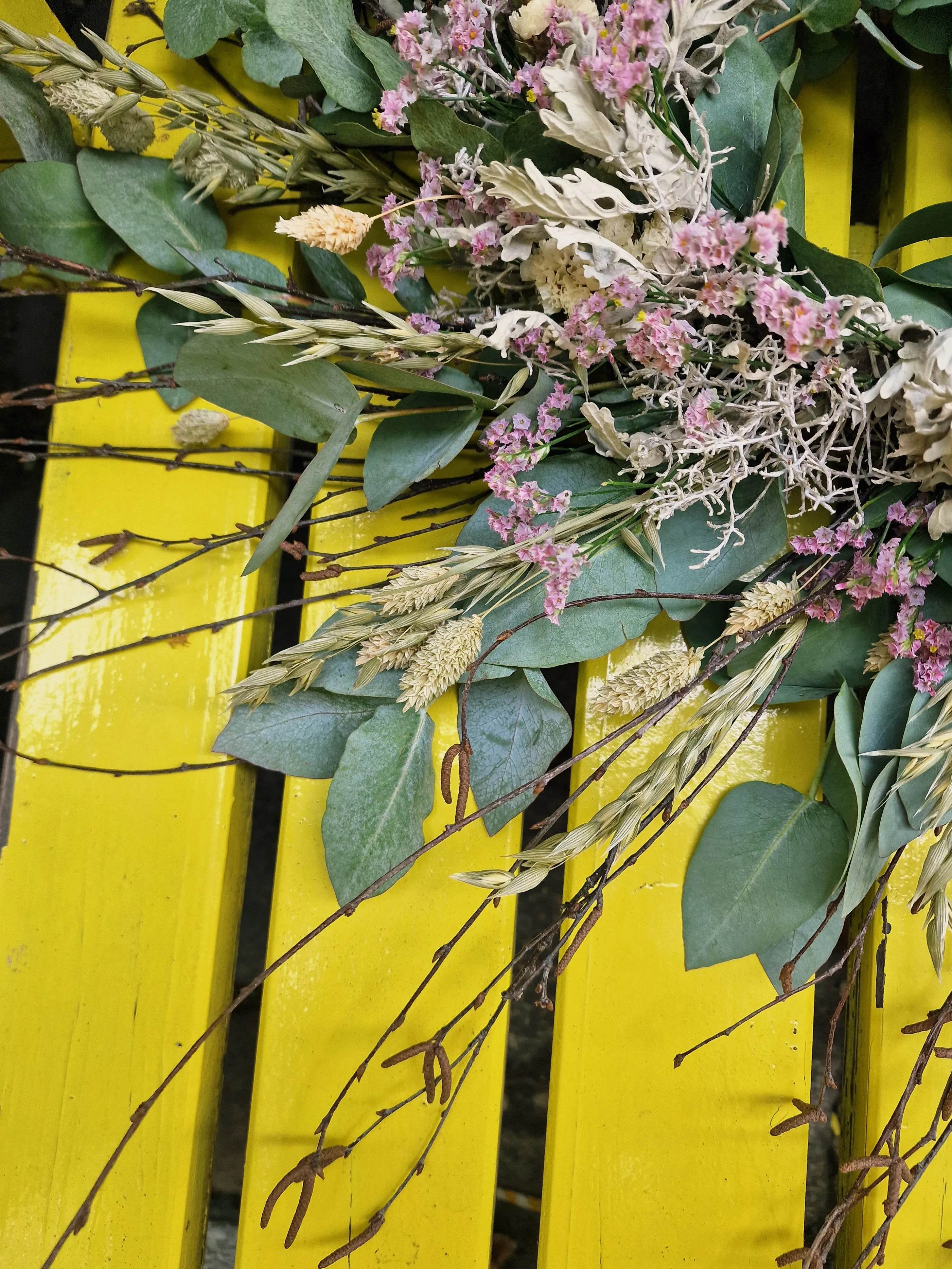 Blumenarrangement auf gelber Holzfläche.