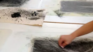 Hand verwischt Kohle auf weißem Papieroberfläche.